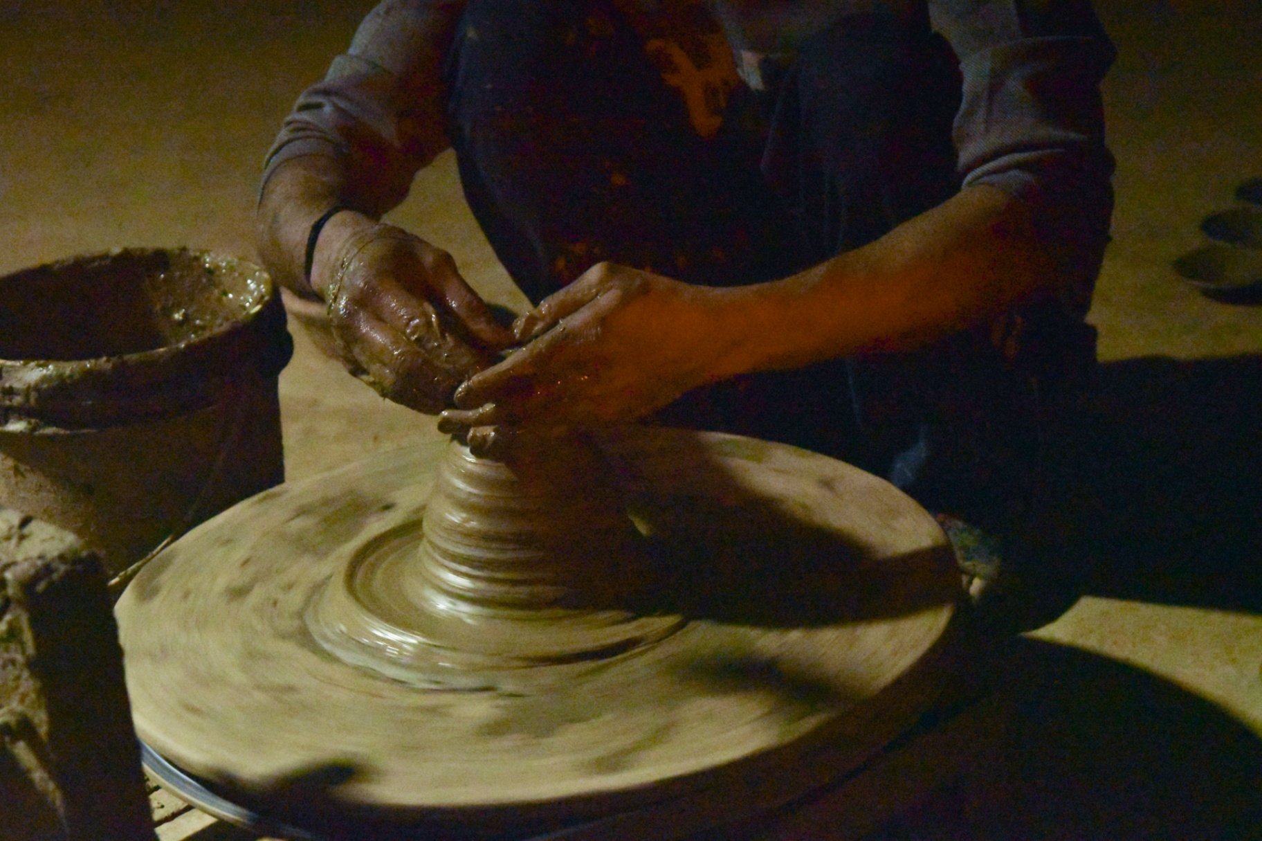 Hands shaping wet clay on a spinning wheel